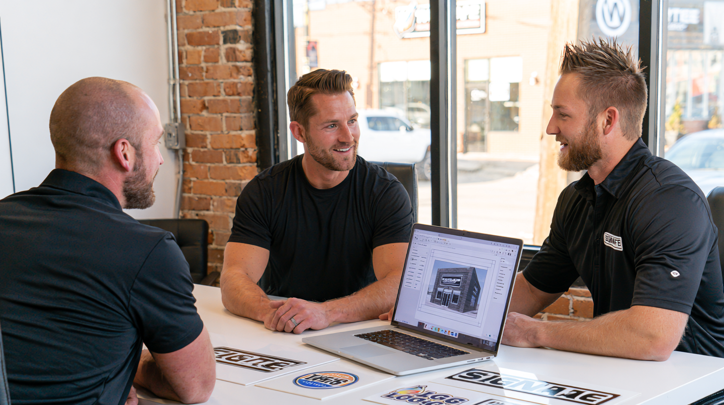 Signage team reviewing sign design on laptop